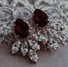 two pairs of brown and white earrings on top of a lace doily with pearls