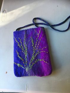 a purple bag with a tree on it sitting on top of a white table next to a blue cord