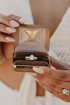 a woman holding an open ring box with two wedding rings in it's hands