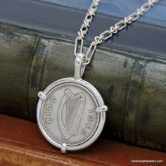 This is a custom order item. Your order will ship within 3-5 business days of payment confirmation. The coin pendant in the listing photos is an example of the finished piece. Excluding the year on the coin, your coin pendant will be the same design as the pictured pendant. Each pendant setting is made by hand (not a machine), and no two coins are exactly alike. If you are looking for a specific year, let me know, I may have it in my collection. This Irish Three Pingin rests in a handcrafted set Heirloom Silver Necklace With Coin Pendant, Antique Stamped Sterling Silver Necklace, Vintage Sterling Silver Coin Jewelry, Classic Handmade Jewelry With Round Pendant, Classic Handmade White Gold Necklace, Classic Silver Necklace For Commemoration, Hallmarked Coin Shaped Sterling Silver Necklaces, Vintage Sterling Silver Jewelry For Commemoration, Heirloom Sterling Silver Round Pendant Necklace