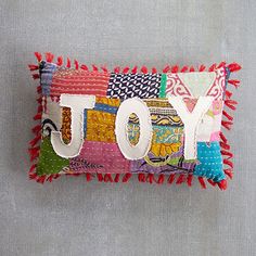 a colorful pillow with the word joy on it and fringe trimming around the edges