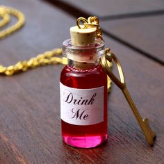 a bottle of drink sitting on top of a wooden table next to a gold chain