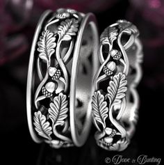 two wedding bands with leaves and pearls on them, sitting next to each other in front of flowers