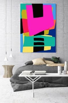 an abstract painting hangs on the wall above a bed