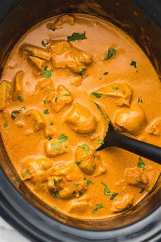 a slow cooker filled with chicken curry and garnished with parsley