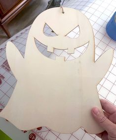 a person holding up a wooden cut out of a ghost