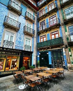 tables and chairs in front of buildings with balconies