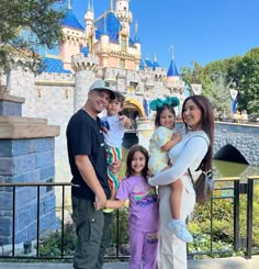 a family poses for a photo in front of the sleeping beauty castle at disneyland world