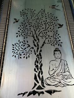 a metal tree with buddha sitting under it