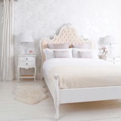 a white bedroom with a bed, nightstands and two lamps on either side of the bed