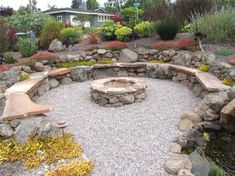 an outdoor fire pit surrounded by rocks and plants