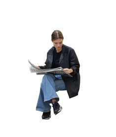 a woman sitting on the ground reading a newspaper