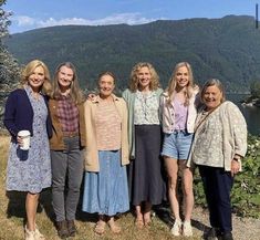 a group of women standing next to each other on top of a grass covered field