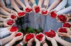 a group of people holding roses in the shape of a circle on top of each other