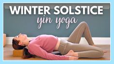 a woman laying on the floor with her eyes closed and hands behind her head, in front of a blue wall that says winter solstice yin yoga