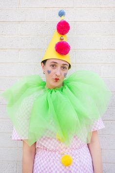 a woman wearing a green tutu skirt and a yellow hat with pom poms