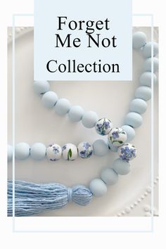 a blue necklace with flowers and tassels hanging from it's side on a white plate