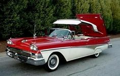 an old red and white car parked on the side of the road with its trunk open