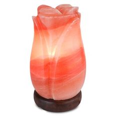 an orange and pink vase sitting on top of a wooden stand