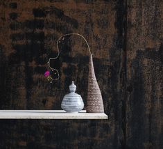 two vases sitting on top of a white shelf