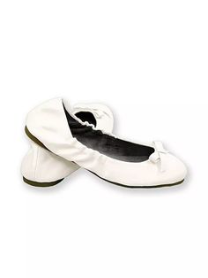 a pair of white ballet shoes with bows on the toe and black soles, all in