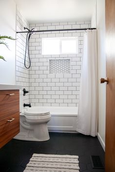 a white toilet sitting in a bathroom next to a bath tub and shower head mounted on a wall