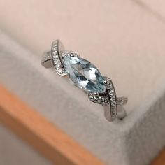 a ring with an aqua blue topazte surrounded by white diamonds in a box