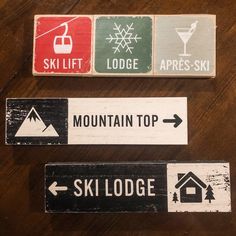 three ski lodge signs on a wooden table