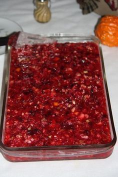 a glass dish filled with cranberry sauce on top of a white table cloth