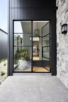 an open door leading into a house with stone walls and black trim on the outside