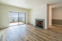 an empty living room with a fireplace and sliding glass doors