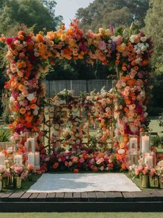 an outdoor ceremony setup with flowers and candles on the ground, surrounded by greenery