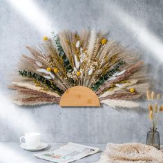 a table topped with a vase filled with flowers next to a wall mounted clock covered in feathers