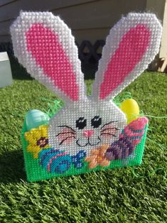 a plastic basket with an easter bunny in it sitting on the grass next to some eggs