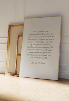 an empty frame with a poem on it sitting next to two framed pictures in front of a white wall