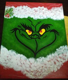 the grin face is painted on a green and red canvas with white snow around it