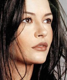 a close up of a woman with long dark hair and brown eyes looking at the camera