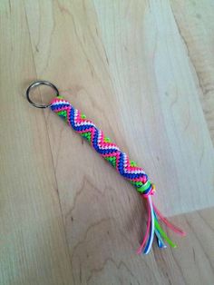 a keychain with a multicolored braid on it sitting on top of a wooden table