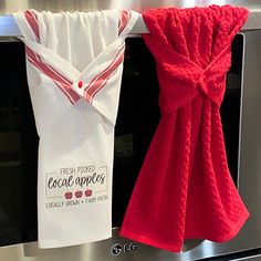 two red and white towels hanging on the side of an oven door, one is folded