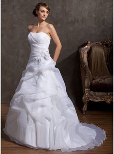 a woman in a white wedding dress standing next to a chair