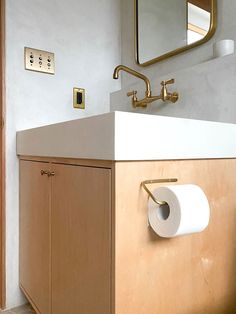 a bathroom with a sink, mirror and toilet paper dispenser