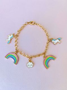 "Unicorn Rainbow Cloud Charm Bracelet This gold charm bracelet is adorable and perfect for all ages! Everyone loves unicorns! Comes with 5 charms.  *Size: 7.5\" *Charms:     (2) Blue Unicorns  (2) Pastel Rainbows  (1) Cloud *Lobster Claw Closure If you have any questions about this or any other product, don't hesitate to ask!  💕  🍭 Candy Painted Boutique 🍭" Cute Rainbow Charm Bracelet As Gift, Cute Rainbow Charm Bracelet For Gift, Playful Rainbow Charm Bracelet For Gift, Playful Rainbow Charm Bracelet For Gifts, Cute Gold Bracelets With Charms, Cute Gold Charm Bracelet For Birthday, Whimsical Gold Charm Bracelet, Candy Paint, Tissue Paper Wrapping