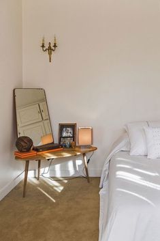 a bed room with a neatly made bed and a large mirror on the wall next to it