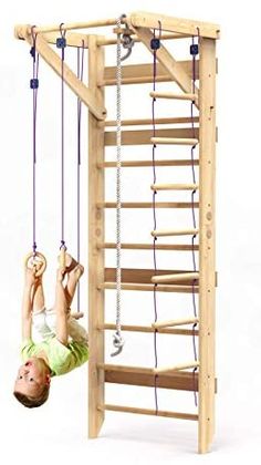 a child is hanging upside down on a wooden structure with ropes attached to the ceiling