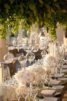 a long table is set with white flowers and wine glasses