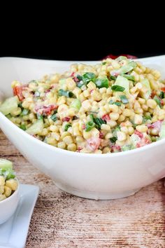 a white bowl filled with corn salad next to another bowl