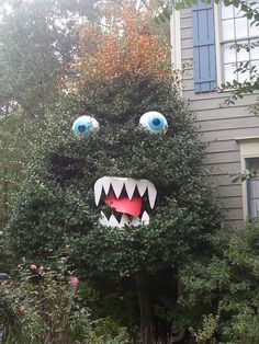 a fake monster head in front of a house with large blue eyes and sharp teeth