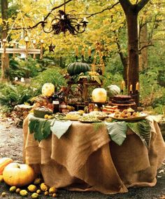 a table covered in burlap cloth with pumpkins and other food on it