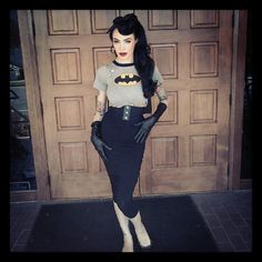 a woman dressed as batman standing in front of a door