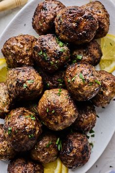 some meatballs on a plate with lemon wedges and parsley sprinkled